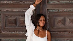 La surfista Patricia Ornelas vestida de blanco frente a una puerta de madera.